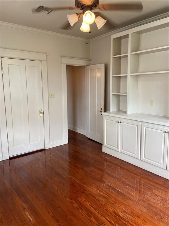 unfurnished bedroom with dark hardwood / wood-style flooring, ornamental molding, and ceiling fan