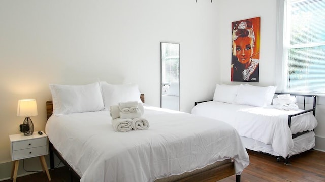 bedroom with multiple windows and dark wood-type flooring