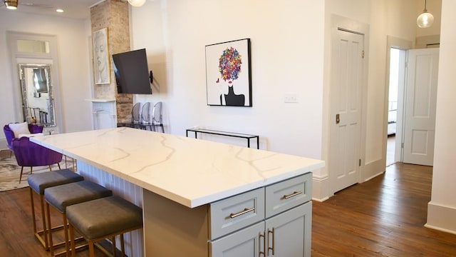 kitchen featuring gray cabinets, a kitchen island, dark hardwood / wood-style flooring, decorative light fixtures, and light stone countertops