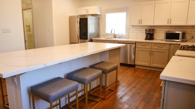 kitchen with appliances with stainless steel finishes, a kitchen bar, dark hardwood / wood-style floors, and white cabinets