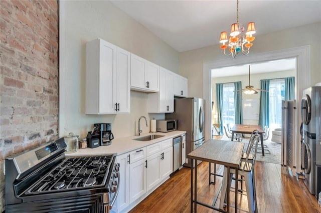 kitchen featuring decorative light fixtures, sink, dark hardwood / wood-style floors, appliances with stainless steel finishes, and white cabinetry