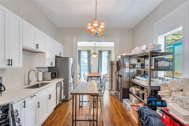 kitchen with white cabinets, pendant lighting, sink, hardwood / wood-style flooring, and stainless steel appliances