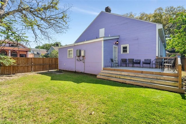 rear view of property with a wooden deck and a yard