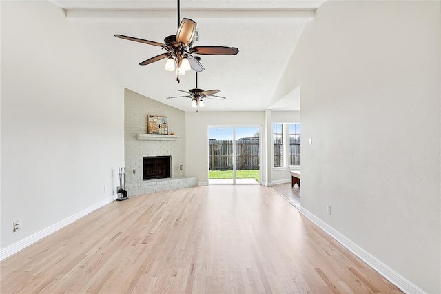 unfurnished living room featuring a fireplace, beam ceiling, light wood-type flooring, and ceiling fan