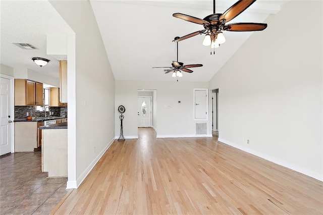 unfurnished living room featuring light hardwood / wood-style flooring, sink, high vaulted ceiling, and ceiling fan