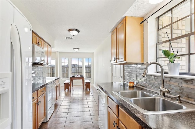 kitchen featuring backsplash, sink, and white appliances