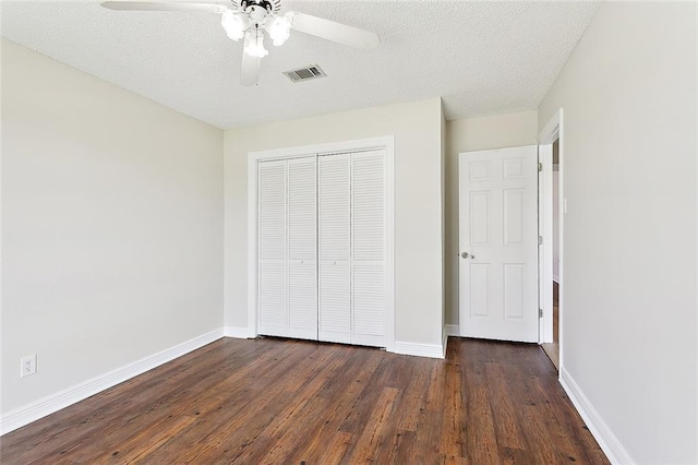 unfurnished bedroom featuring a closet, ceiling fan, a textured ceiling, and dark hardwood / wood-style floors