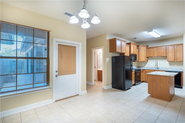 kitchen featuring an inviting chandelier, pendant lighting, a kitchen island, light stone counters, and black appliances