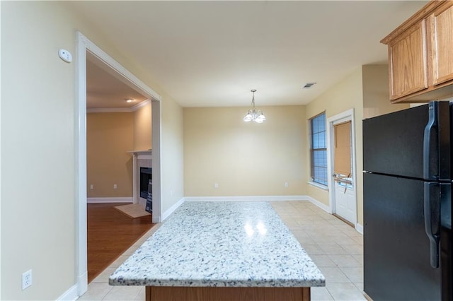 kitchen with light hardwood / wood-style floors, a chandelier, black fridge, hanging light fixtures, and ornamental molding