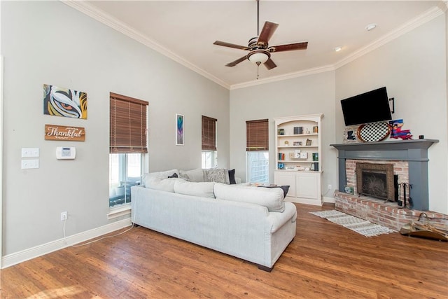 living room with ornamental molding, hardwood / wood-style floors, ceiling fan, and a fireplace