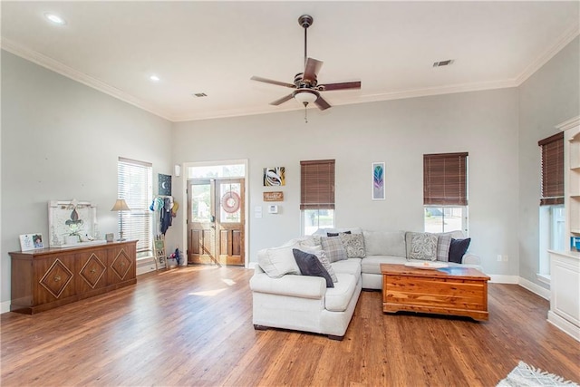 living room featuring wood-type flooring, plenty of natural light, ornamental molding, and ceiling fan