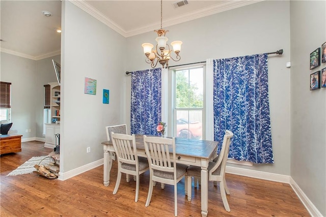 dining area with hardwood / wood-style flooring, ornamental molding, and an inviting chandelier