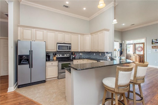 kitchen with crown molding, decorative light fixtures, stainless steel appliances, and kitchen peninsula