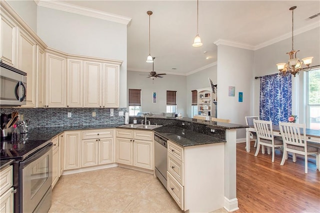 kitchen featuring cream cabinetry, sink, stainless steel appliances, and hanging light fixtures