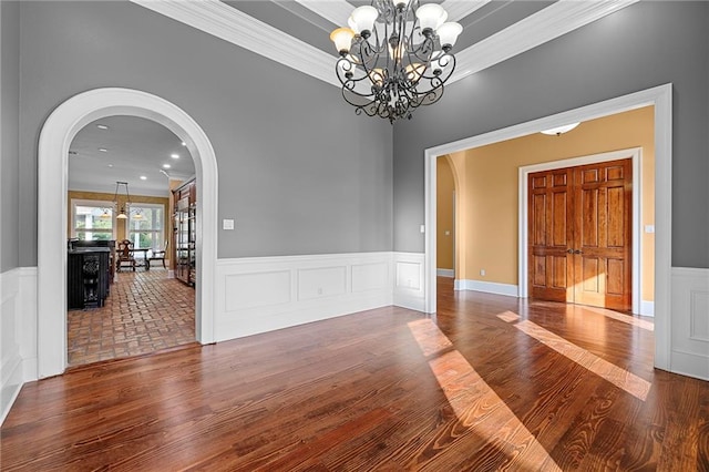 unfurnished dining area with an inviting chandelier, ornamental molding, and hardwood / wood-style flooring