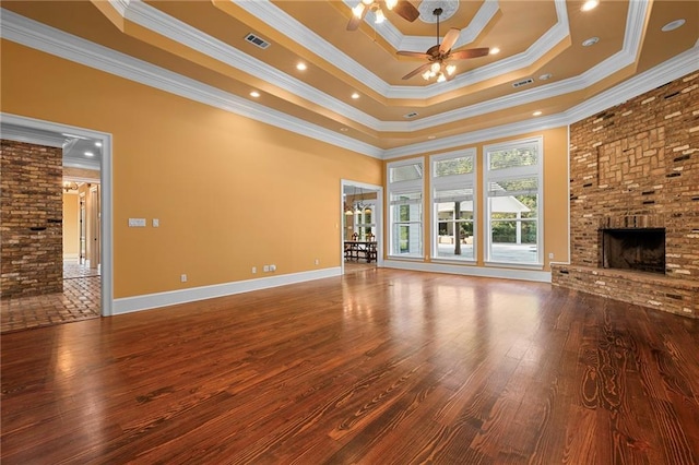 65520 S Hickory Dr, Pearl River, LA 70452 - unfurnished living room featuring a ceiling fan, wood finished floors, a brick fireplace, crown molding, and a tray ceiling