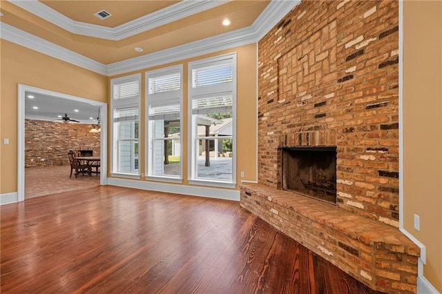 65520 S Hickory Dr, Pearl River, LA 70452 - unfurnished living room featuring wood finished floors, a fireplace, brick wall, crown molding, and baseboards