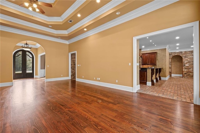 65520 S Hickory Dr, Pearl River, LA 70452 - spare room featuring arched walkways, a ceiling fan, dark wood-style flooring, ornamental molding, and a tray ceiling