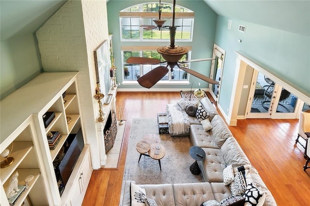 living room with ceiling fan, high vaulted ceiling, wood-type flooring, and a fireplace