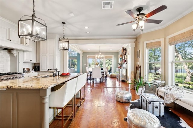 kitchen featuring a breakfast bar, hardwood / wood-style flooring, decorative light fixtures, and light stone counters