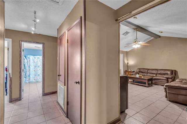 hallway with vaulted ceiling with beams, a textured ceiling, and light tile patterned floors