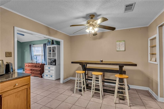 tiled dining room with crown molding, a textured ceiling, and ceiling fan