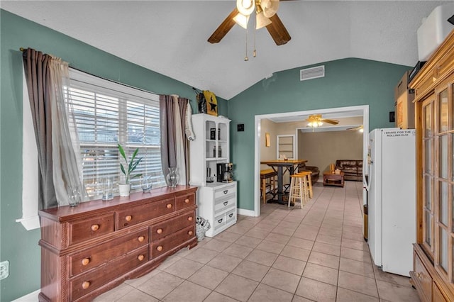 interior space featuring lofted ceiling, white refrigerator, light tile patterned floors, white cabinets, and ceiling fan