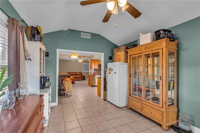 kitchen featuring lofted ceiling, ceiling fan, light tile patterned floors, and white refrigerator