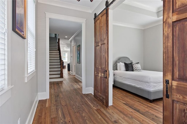 bedroom featuring dark hardwood / wood-style flooring, a barn door, and crown molding