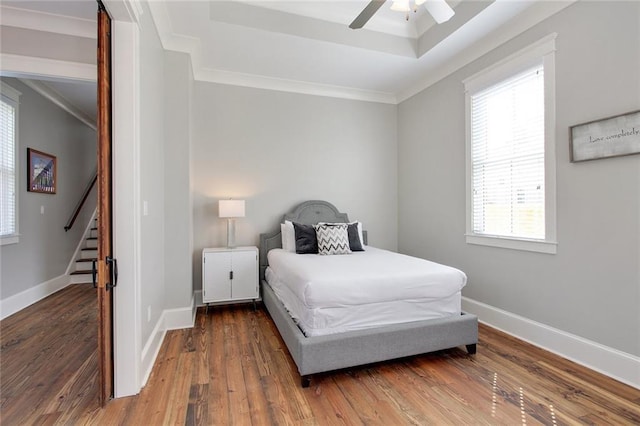 bedroom with a tray ceiling, crown molding, dark hardwood / wood-style floors, and ceiling fan