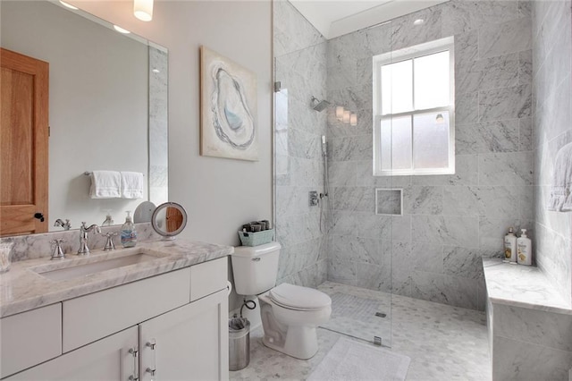 bathroom with toilet, tiled shower, and vanity