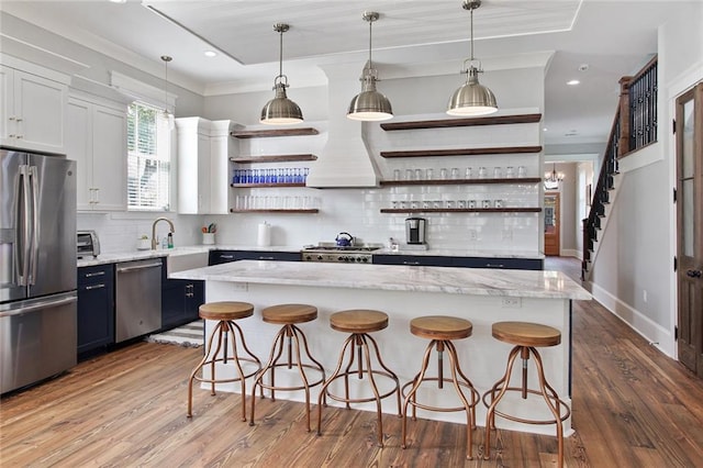 kitchen featuring a center island, white cabinetry, stainless steel appliances, hanging light fixtures, and a breakfast bar area