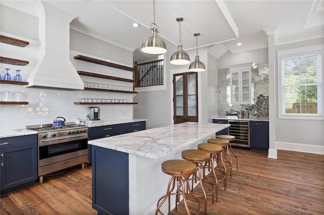 kitchen with blue cabinetry, wine cooler, stainless steel range, white cabinets, and a kitchen breakfast bar