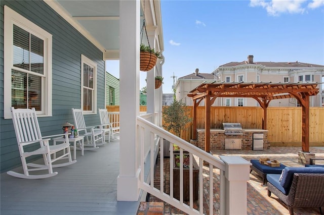 wooden terrace featuring a porch, a pergola, exterior kitchen, and grilling area