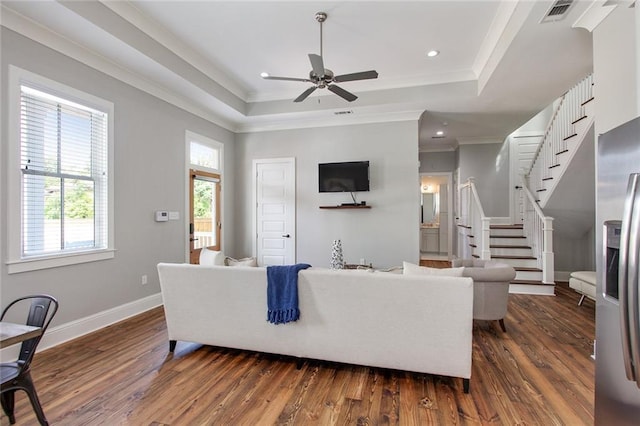 living room with ceiling fan, ornamental molding, a raised ceiling, and dark hardwood / wood-style floors