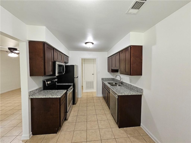 kitchen featuring ceiling fan, appliances with stainless steel finishes, light tile patterned flooring, dark brown cabinetry, and sink