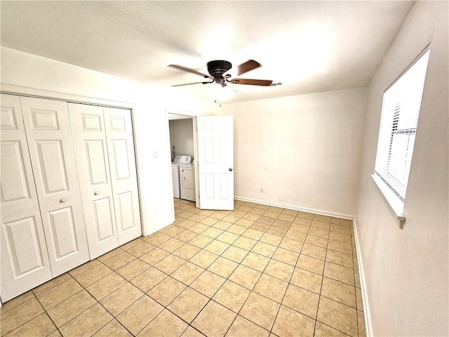 unfurnished bedroom featuring a closet, light tile patterned floors, washer and clothes dryer, and ceiling fan