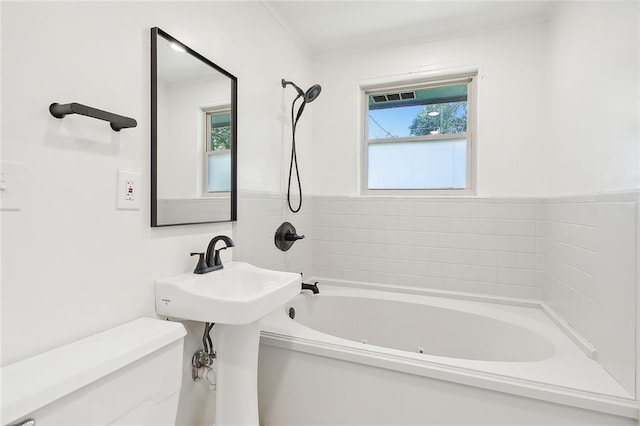 bathroom featuring a healthy amount of sunlight, sink, a bath, and toilet