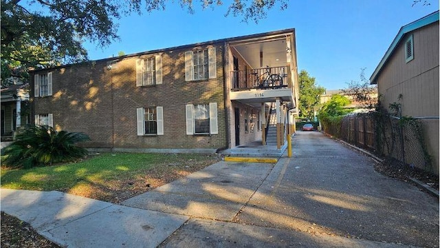 1114 N Dorgenois St, New Orleans, LA 70119 - view of front of house featuring brick siding, driveway, a balcony, and fence