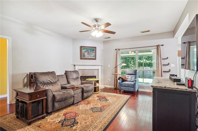 living room featuring ceiling fan, a fireplace, and dark hardwood / wood-style flooring