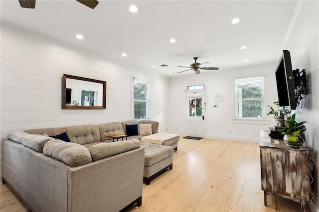 living room with ceiling fan, ornamental molding, and light wood-type flooring