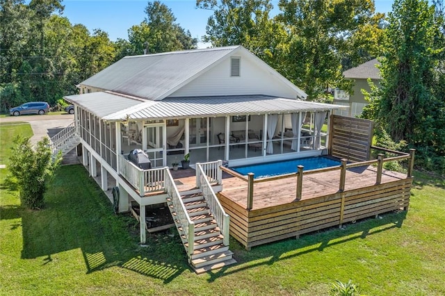 rear view of property with a yard, a wooden deck, and a sunroom