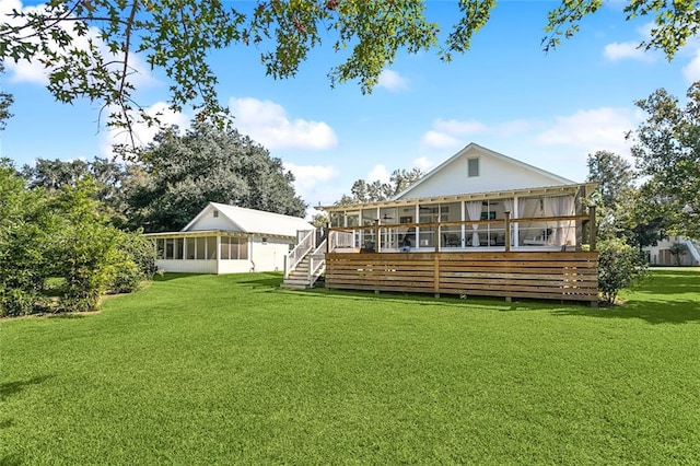 rear view of house featuring a yard, a sunroom, and a wooden deck