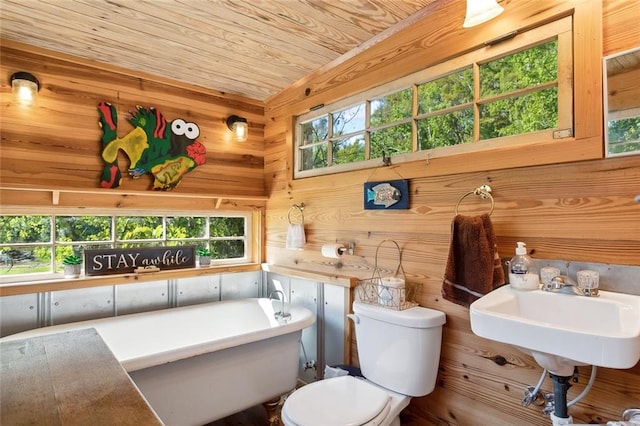 bathroom featuring wooden ceiling, a tub to relax in, toilet, and wood walls