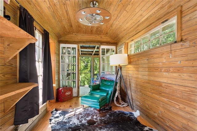 living area with light hardwood / wood-style floors, wood walls, lofted ceiling, and wood ceiling