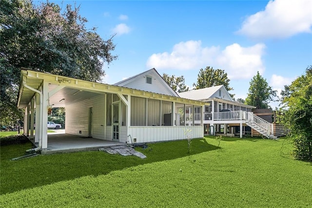 rear view of property featuring a carport, a lawn, and a sunroom