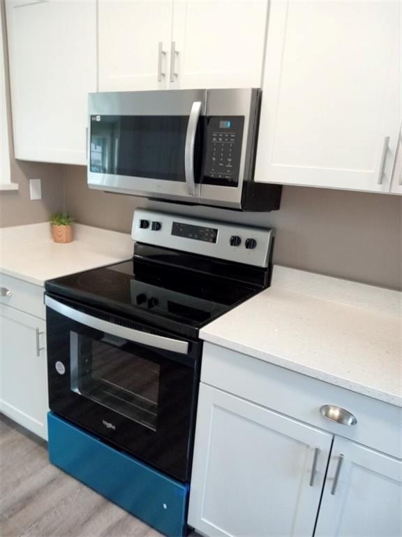 kitchen with white cabinetry, light hardwood / wood-style flooring, and stainless steel appliances