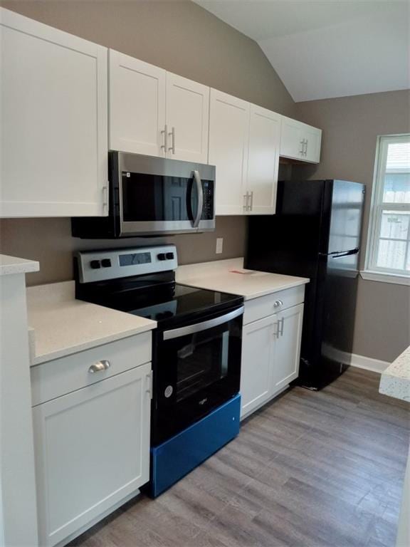 kitchen featuring lofted ceiling, black appliances, white cabinets, and light hardwood / wood-style floors