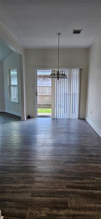 unfurnished dining area featuring a chandelier and dark hardwood / wood-style flooring