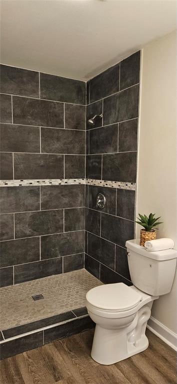 bathroom featuring toilet, hardwood / wood-style flooring, and tiled shower